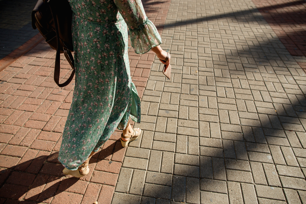 A women in a long, green, floral dress walks in heeled wedges down the streets, not stressing about what to wear in Key West. 