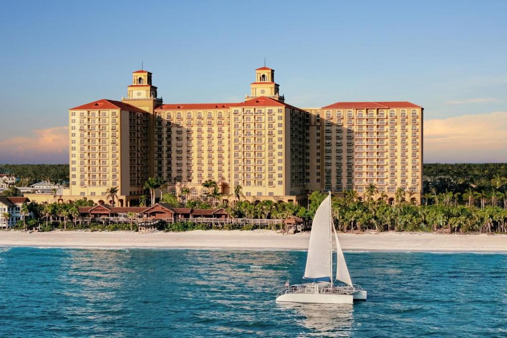 Hotel on the beach with bright blue water and a sailing boat. 