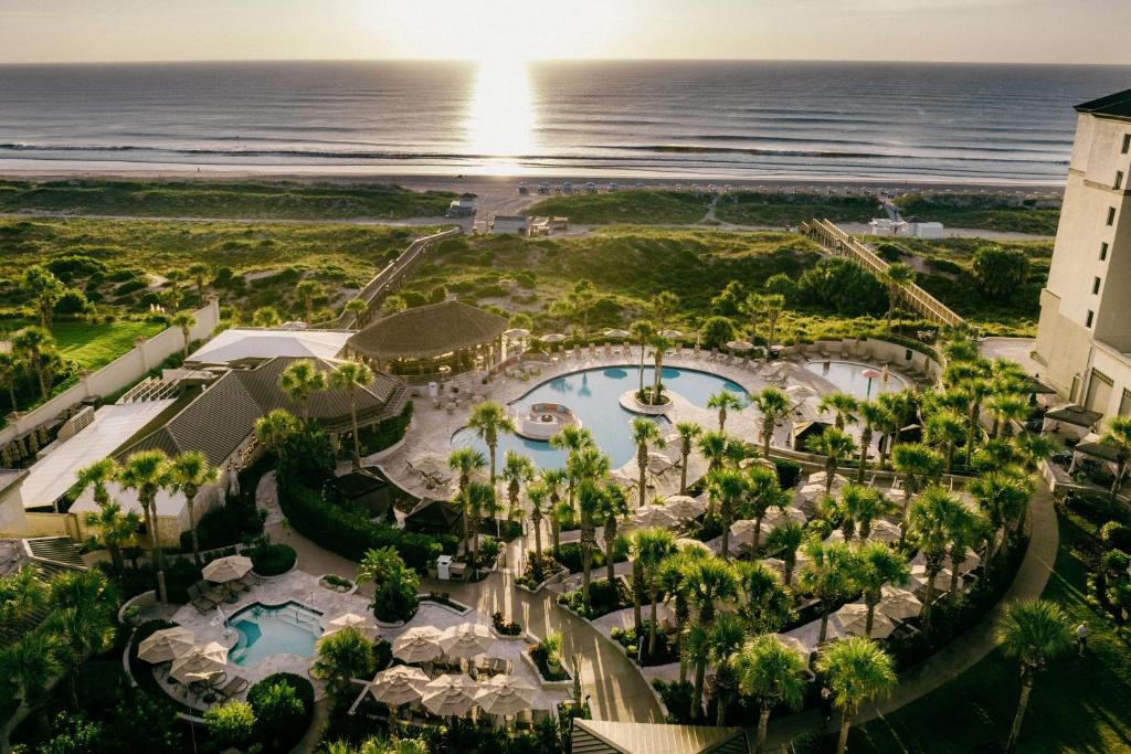 Over of resort hotel shoe lush greenery and pools. You can see the ocean n the background. 