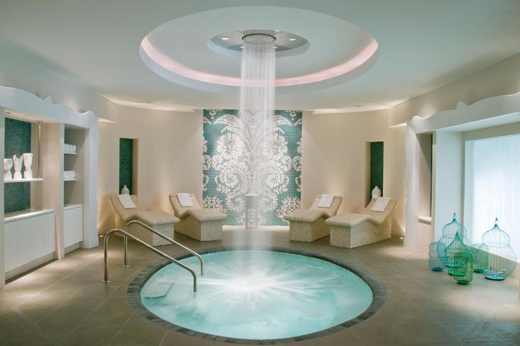 beautiful indoor hot tub with waterfall from the ceiling. the room is round with relaxing spa chairs around it.