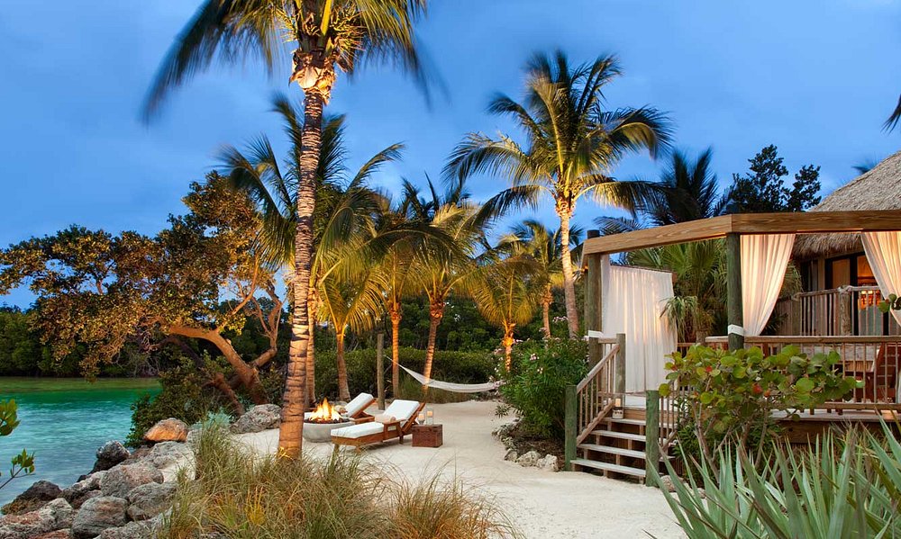 A beachfront bungalow on a private island with chairs and a firepit. This is on of the best spa resorts in Florida. 