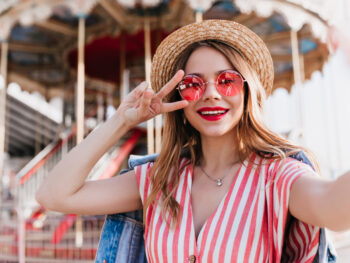 woman standing in front of a carnival ride wearing heart shaped sunglasses