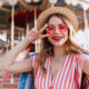 woman standing in front of a carnival ride wearing heart shaped sunglasses