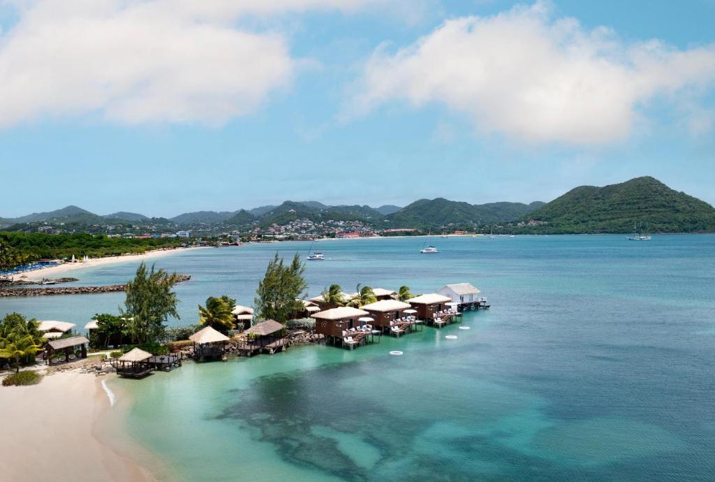 Overwater bungalows in turquoise water with mountina behind. 