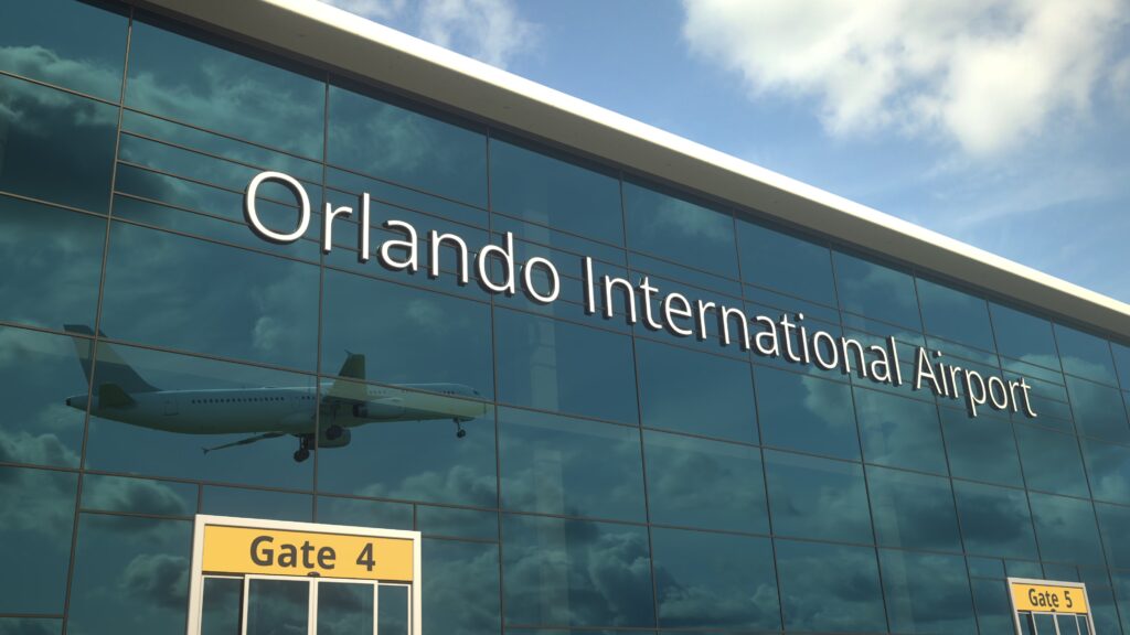 The Orlando International Airport sign is made of glass, and from gate 4 and gate 5 you can see the reflection of a plane taking off: we're wondering if it is going to one of the cheapest places to fly from Orlando.