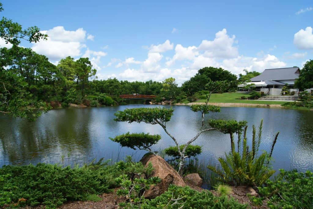 one of the garden with lake a bonsai tree with a covered bridge in the background 